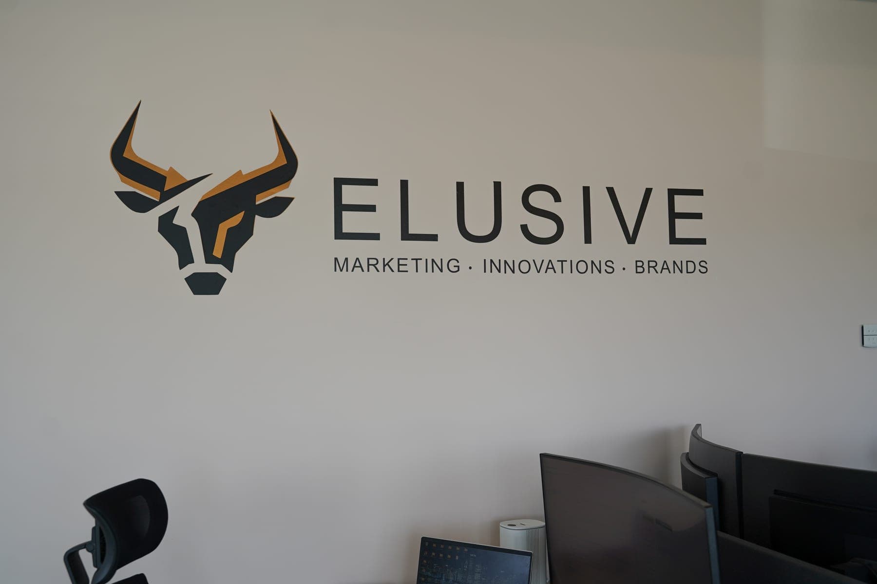 Kantoorruimte met bureaus en het Elusive-logo op de muur